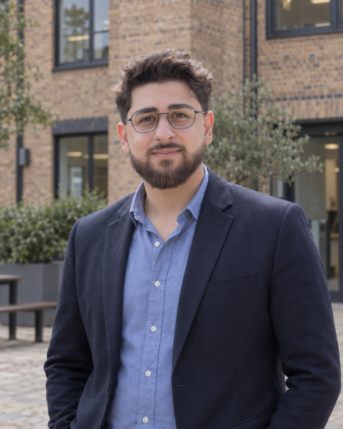 Farhan Ahmadi wearing glasses and a navy jacket in a courtyard